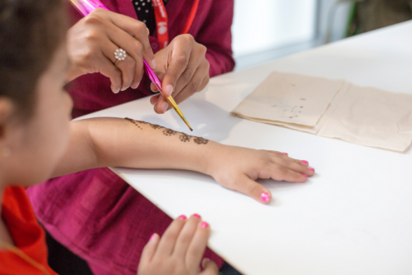 Little girl having henna done on her arm