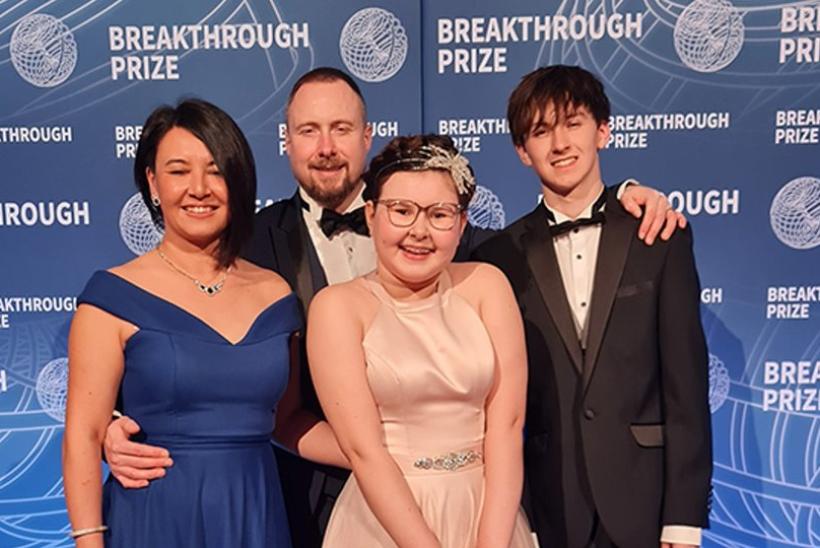 Alyssa with her family on a stage with a background behind them with different blue levels.